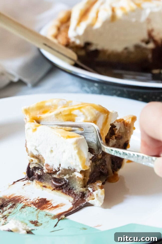 A slice of bourbon pie, with a fork digging into its rich, gooey texture, showing off the pecans and melted chocolate.