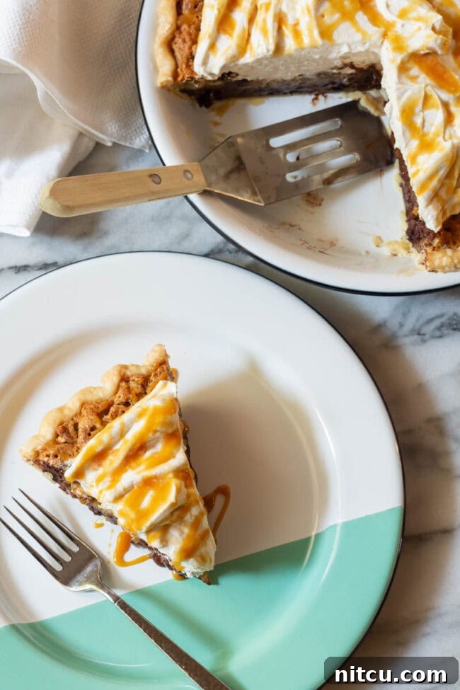 A perfect slice of Kentucky Derby Pie, glistening with its rich filling and topped with a swirl of salted caramel whipped cream, rests on a beautiful white and green plate.