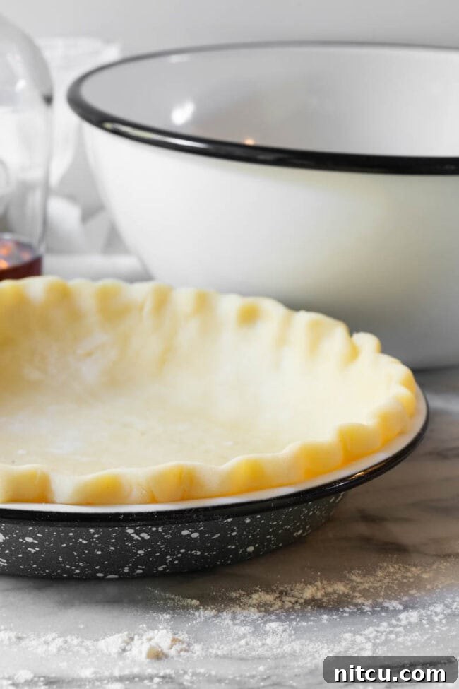An unbaked pie crust, perfectly crimped, waiting in a pie pan.