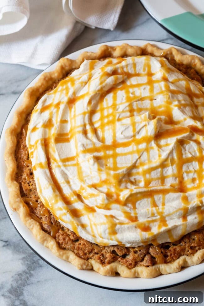 A generous dollop of fluffy salted caramel whipped cream crowns a slice of Kentucky Derby Pie.