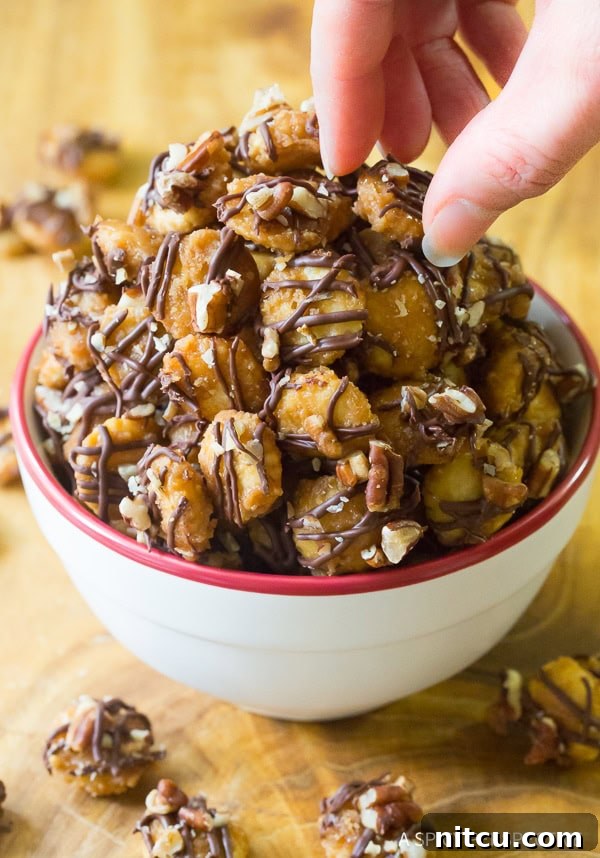 Hand picking up pieces of Christmas crack candy from a white bowl, showing its tempting appeal.