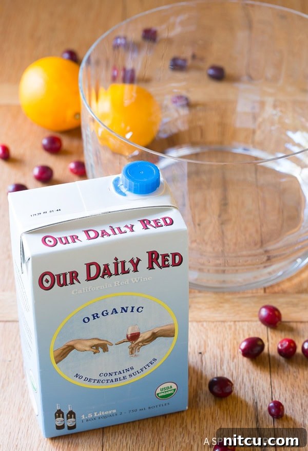 A neatly arranged box of red wine positioned next to an empty, clear glass punch bowl, signifying the initial steps in creating our large batch holiday cocktail.