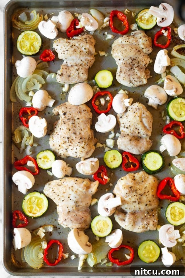 Sliced zucchini and mushrooms on a cutting board, prepared for the sheet pan cacciatore recipe