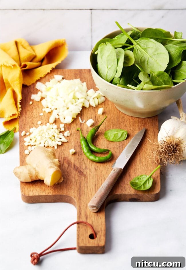 Ingredients for Saag Paneer on a wood cutting board.