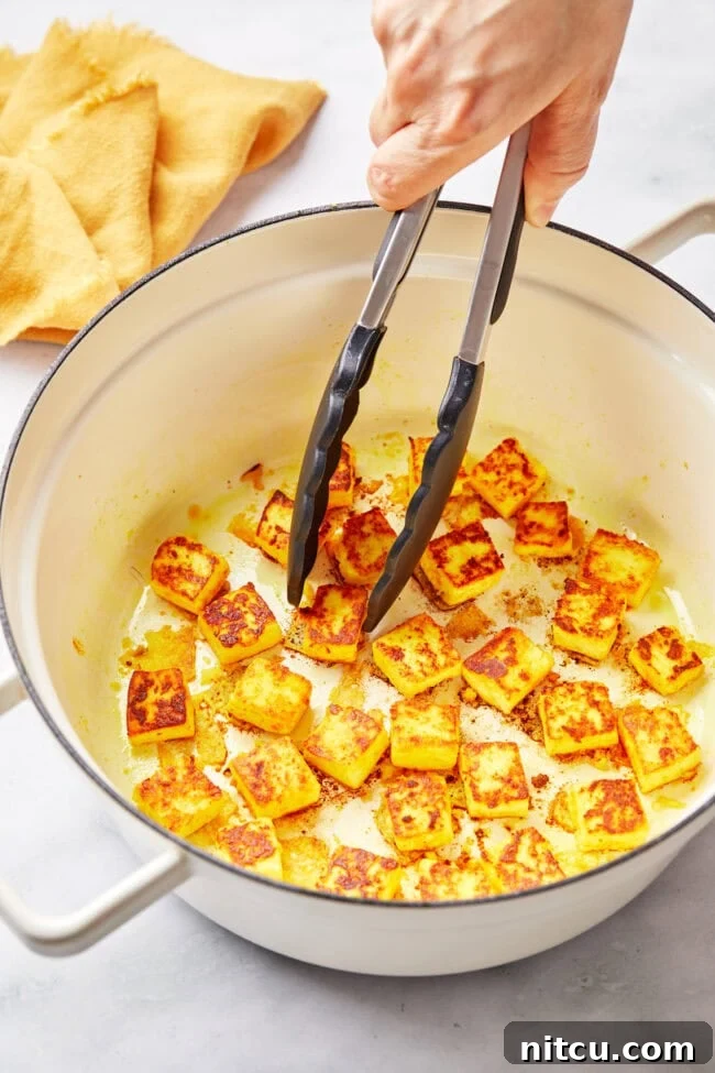 Hand searing the paneer in pan to get a golden crust.
