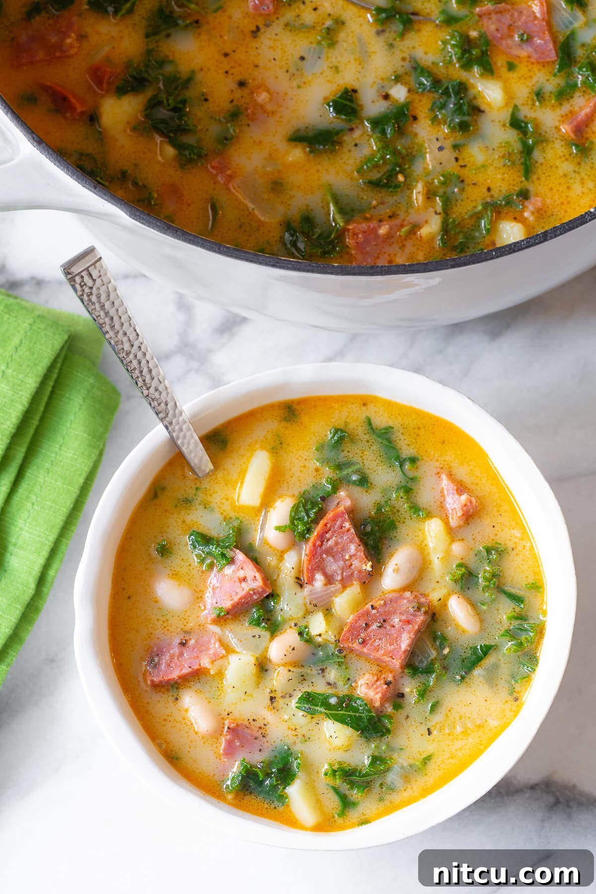 A hearty pot of Portuguese Caldo Verde soup, an overhead view showcasing sausage, potatoes, and kale.