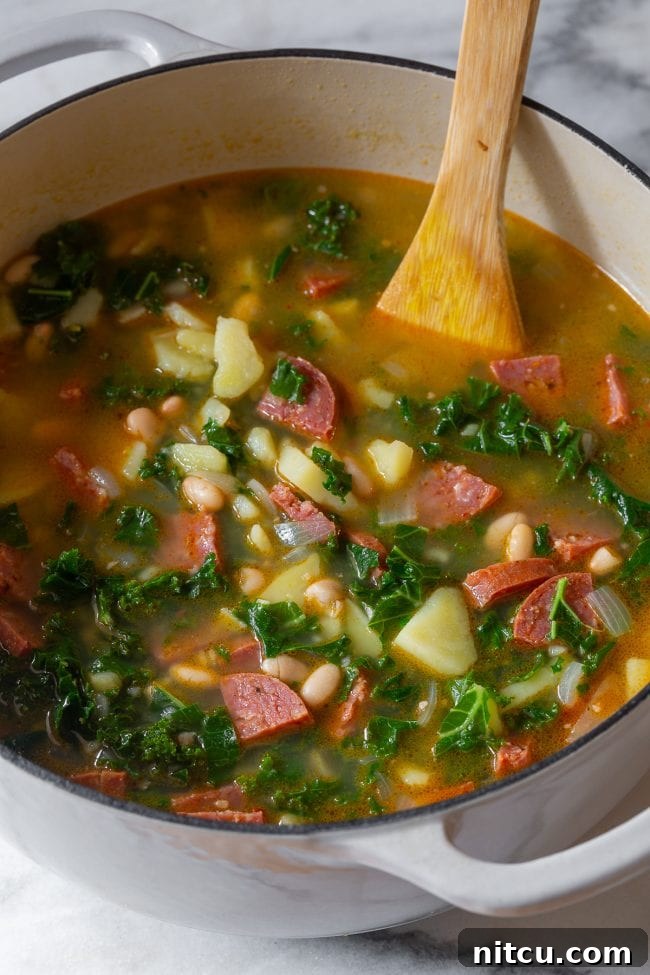 Close-up of Portuguese Caldo Verde soup simmering in a pot, showcasing the vibrant greens and chunky ingredients.