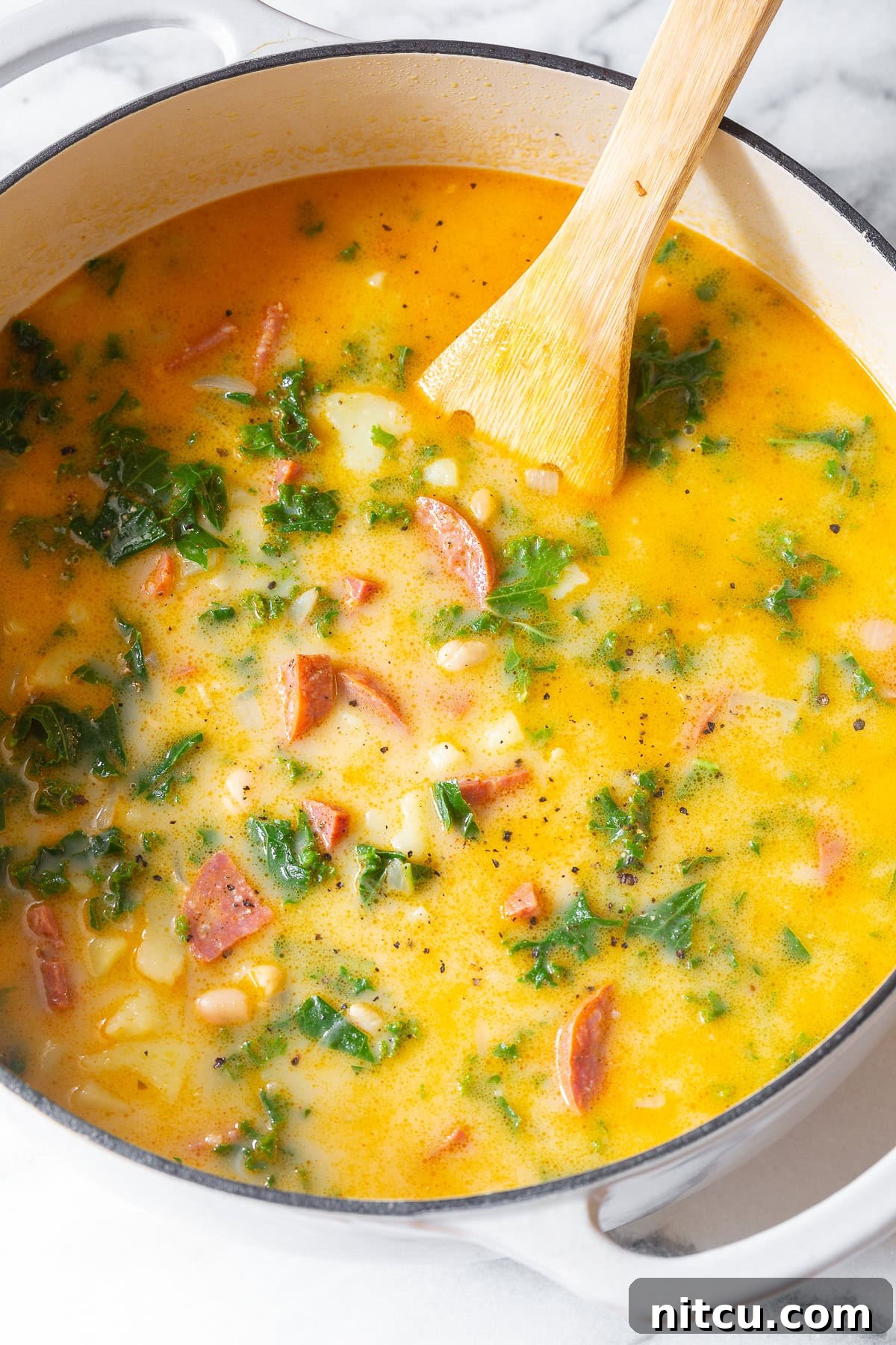 A large pot of green soup, also known as Caldo Verde or Kale Soup, with chunks of sausage visible.