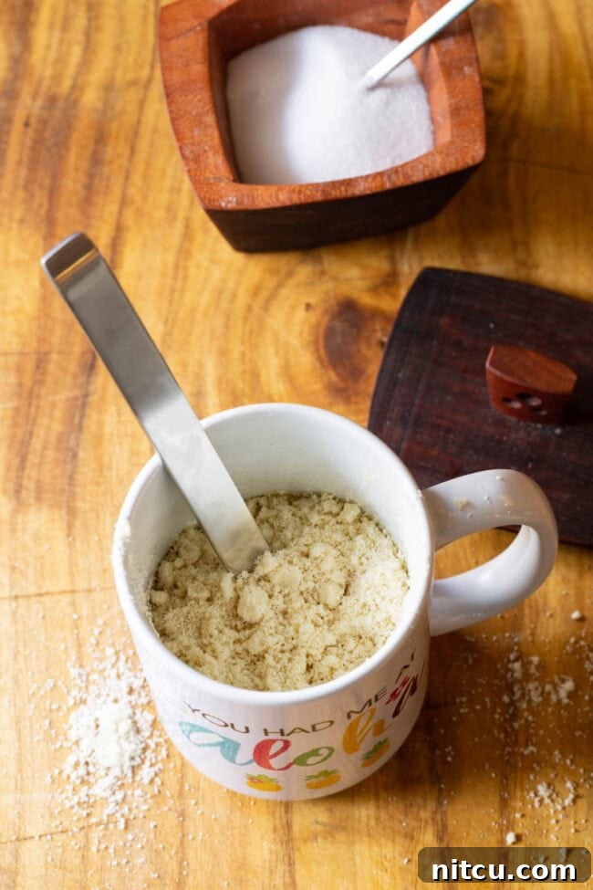Mug with almond flour being mixed with a metal spoon.