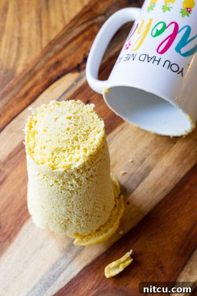 Loaf of magic mug bread on a cutting board next to the now empty mug.