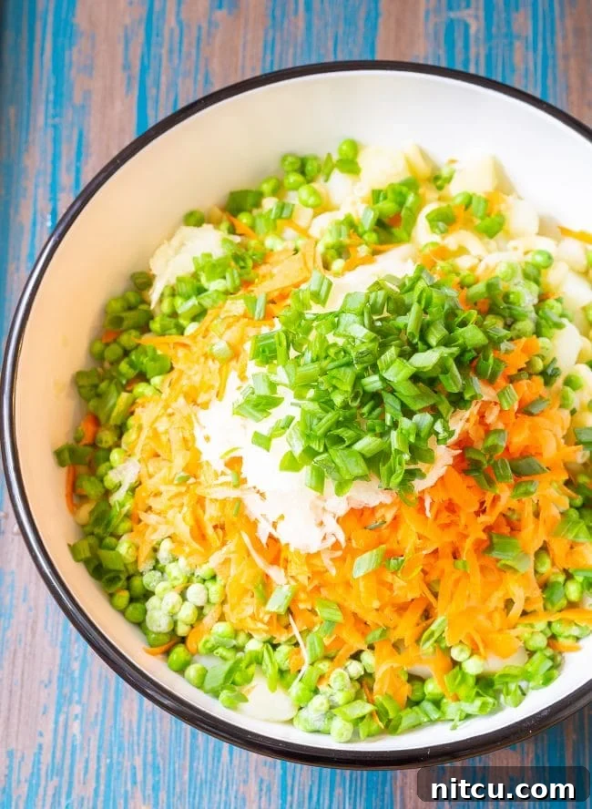 Ingredients for Hawaiian style macaroni salad in a large mixing bowl before being mixed, showing fresh vegetables and pasta.