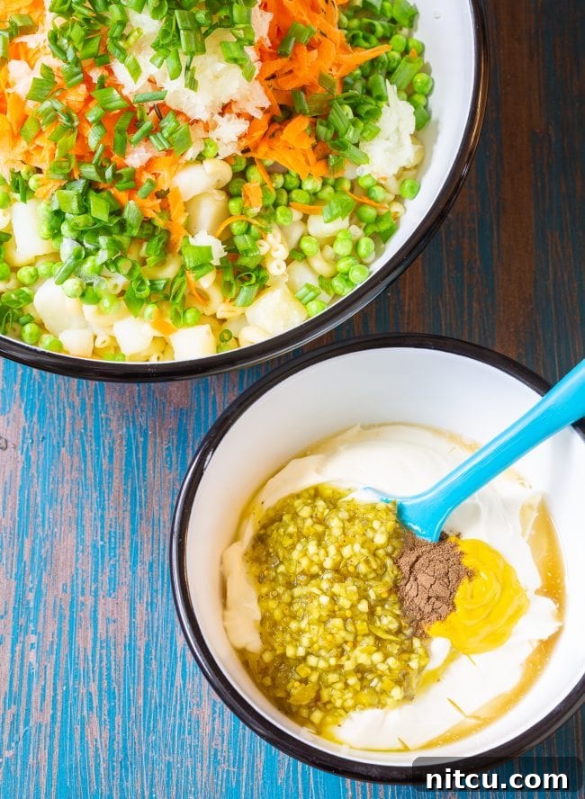 Pasta salad in one bowl with the dressing being mixing in another, smaller bowl, illustrating the preparation process.