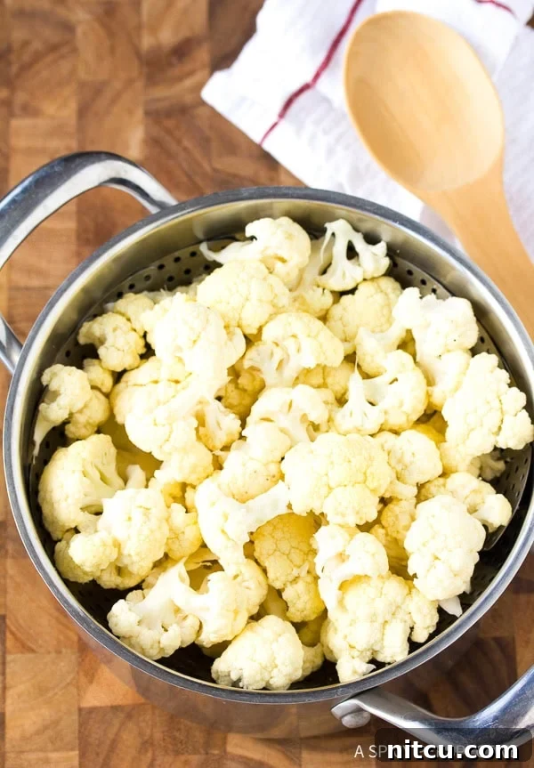 Freshly cut cauliflower florets resting in a steaming basket, ready for preparation to become delicious low carb crackers.