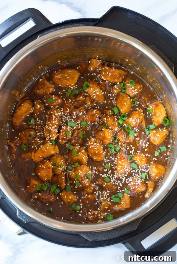 Overhead shot of perfectly cooked sesame chicken simmering in a rich, sticky sauce inside an Instant Pot.
