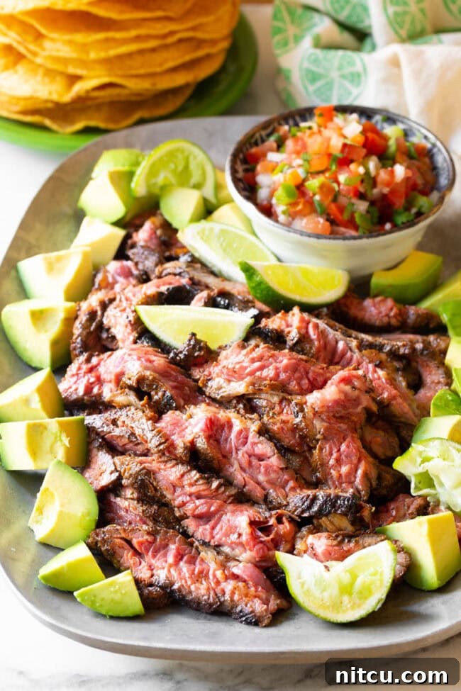 Perfectly seared Carne Asada steak, garnished with fresh avocado and lime wedges, ready to be enjoyed.
