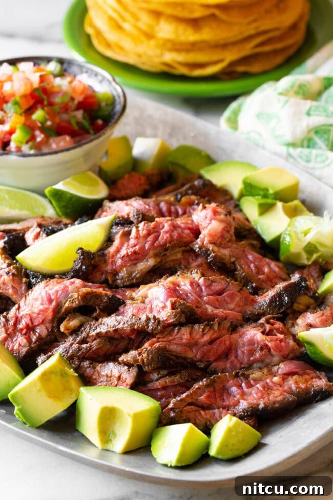 Cooked and thinly sliced Carne Asada steak arranged on a platter, ready for serving.