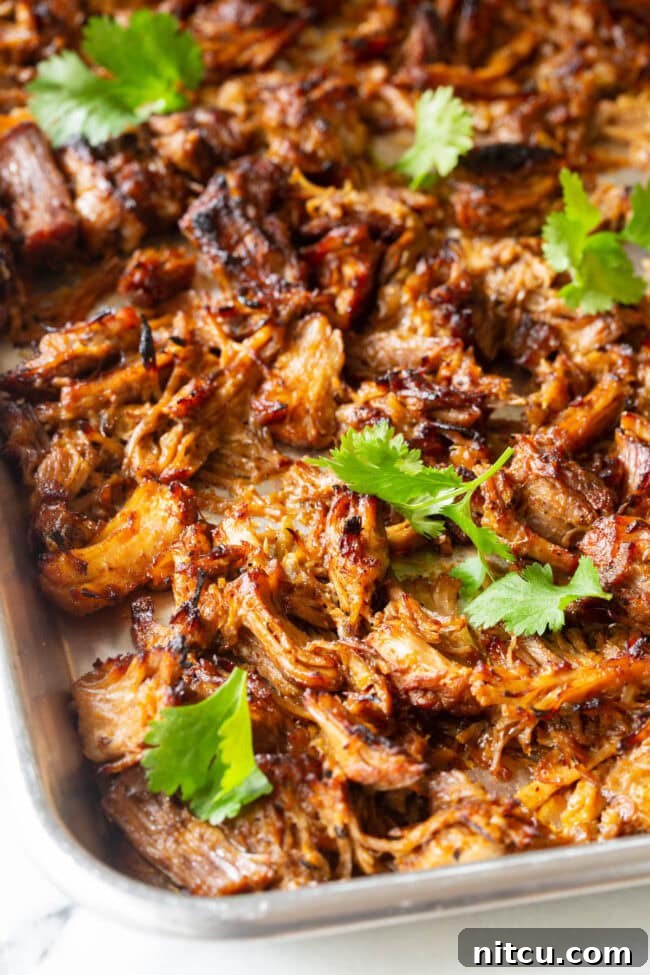 Instant Pot Carnitas spread on a baking sheet, ready for broiling to achieve crispiness