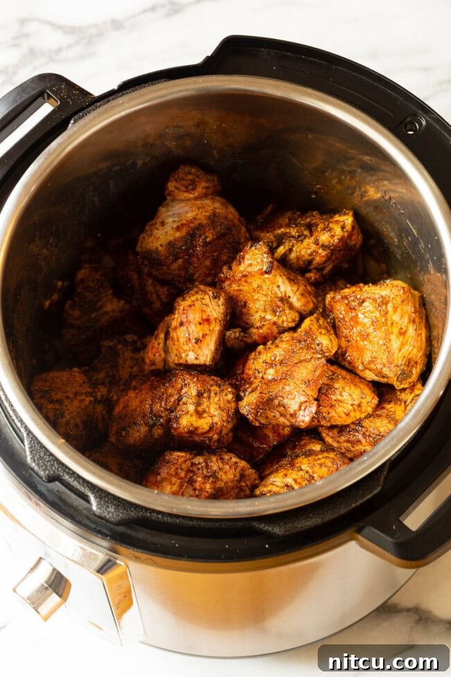 Chunks of pork browning in the pressure cooker for Instant Pot Carnitas