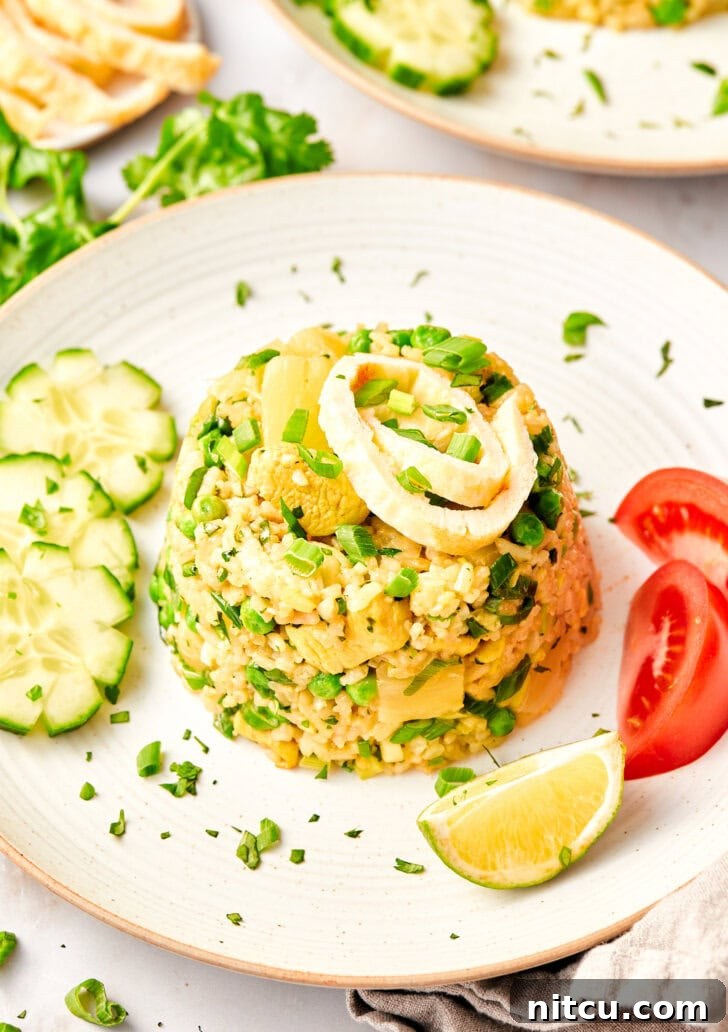 A perfectly plated mound of Thai fried rice, garnished with fresh tomatoes, cucumbers, and lime wedges, ready to be enjoyed.