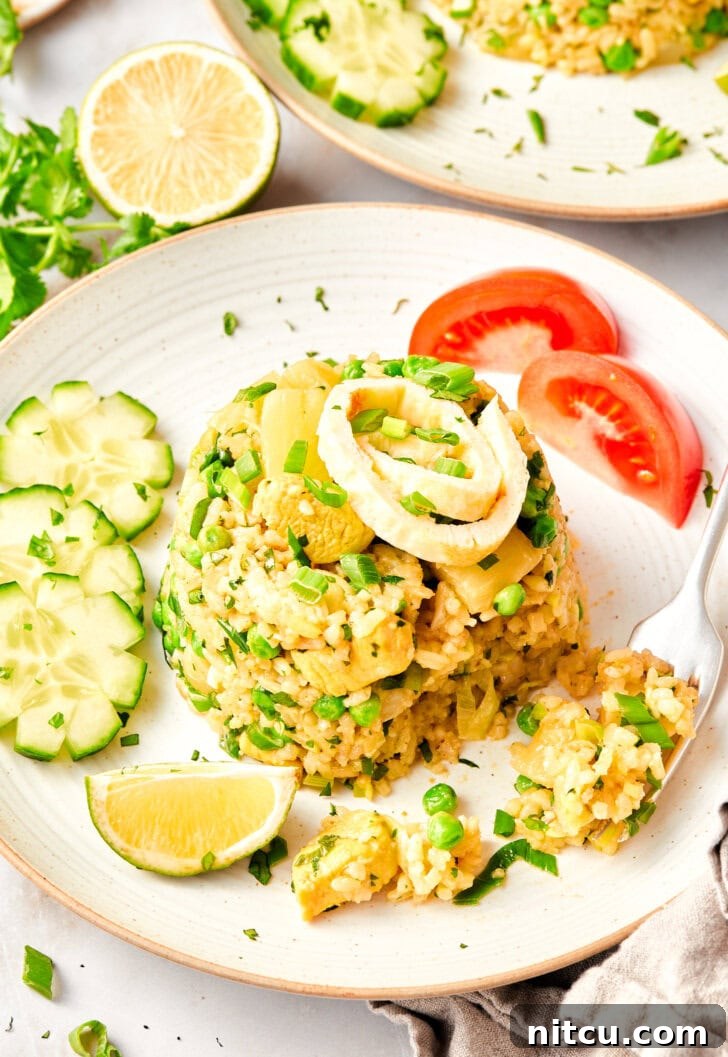 Exquisite Thai fried rice, topped with fresh green onions, presented beautifully on a plate.