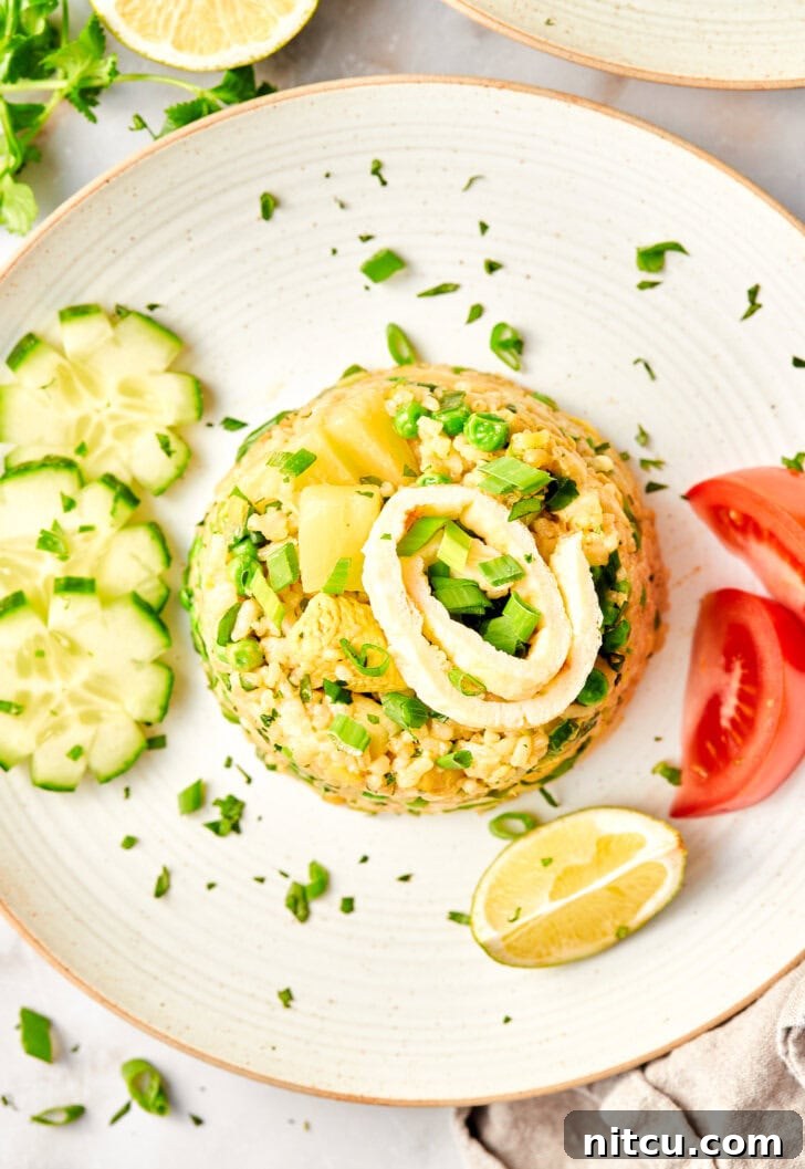 A serving of perfect Thai Fried Rice on a plate, surrounded by fresh cucumbers, tomatoes, lime wedges, and chopsticks, ready for a delicious meal.