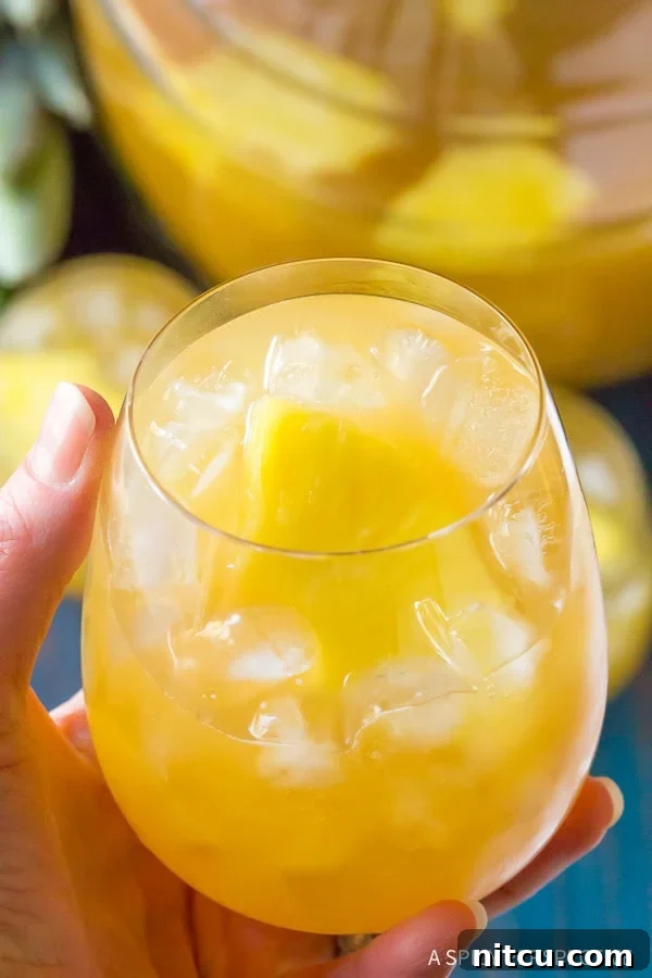 A hand holding a glass of Goombay Smash, showcasing the vibrant colors of this popular Caribbean cocktail