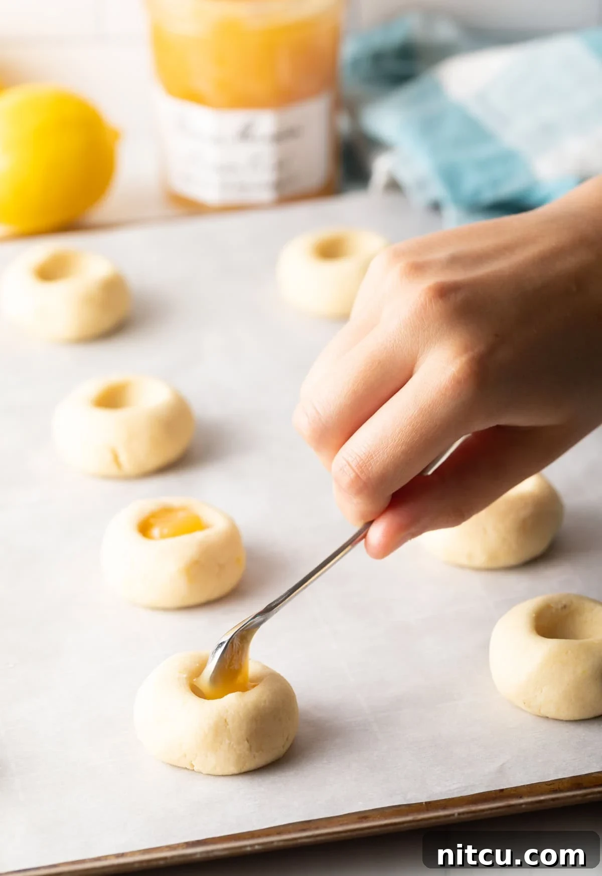 Using the smallest little spoon to put a dollop of custard into the indent of the dough