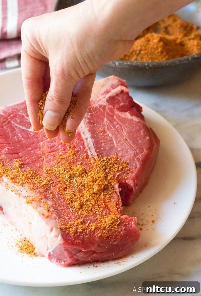 A hand gently pouring spices into a bowl, starting the process of making homemade steak seasoning.
