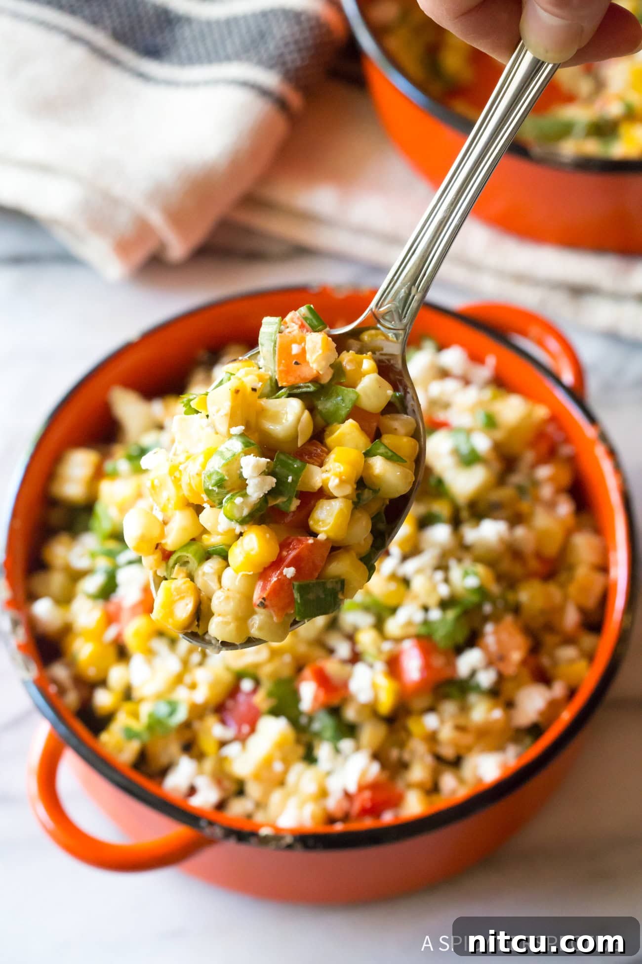 Closeup of a spoon lifting a perfect scoop of vibrant Mexican Street Corn Salad from the bowl, ready to be enjoyed.