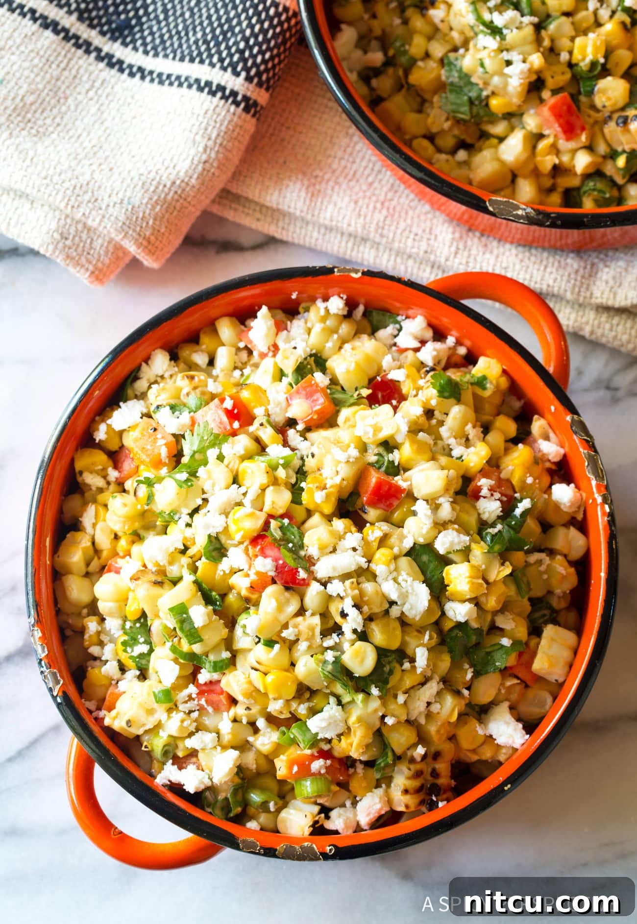Overhead view of a beautifully prepared grilled Mexican street corn salad in a vibrant bowl, garnished with fresh herbs and cheese.