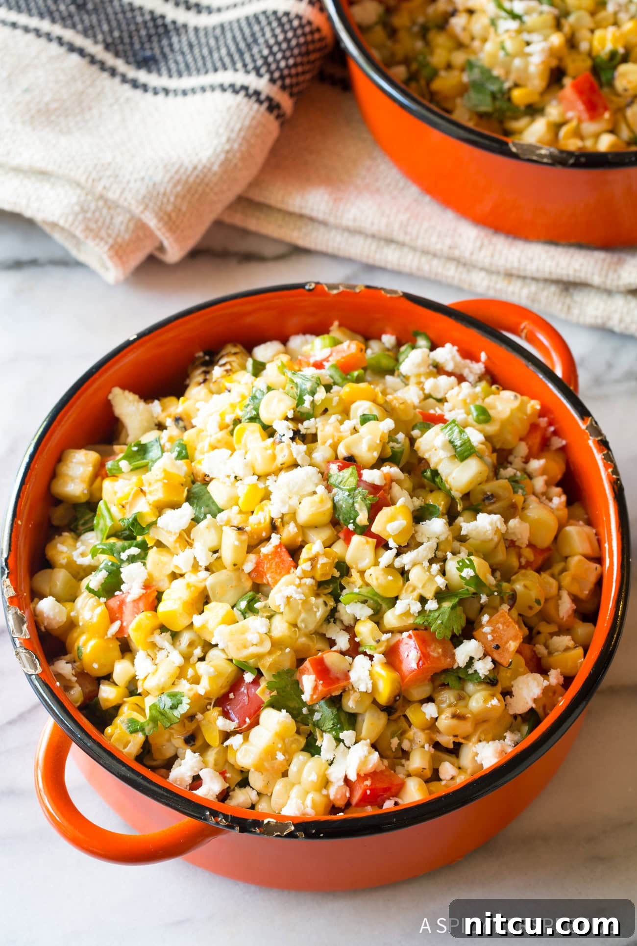 Closeup of Mexican Street Corn Salad served in a vibrant orange bowl, ready to be enjoyed with a spoon.