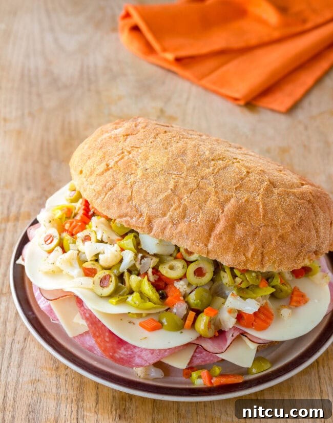 A stunning New Orleans Muffuletta sandwich, freshly made and sliced, showcasing its impressive layers of meat, cheese, and olive salad, ready to be enjoyed.