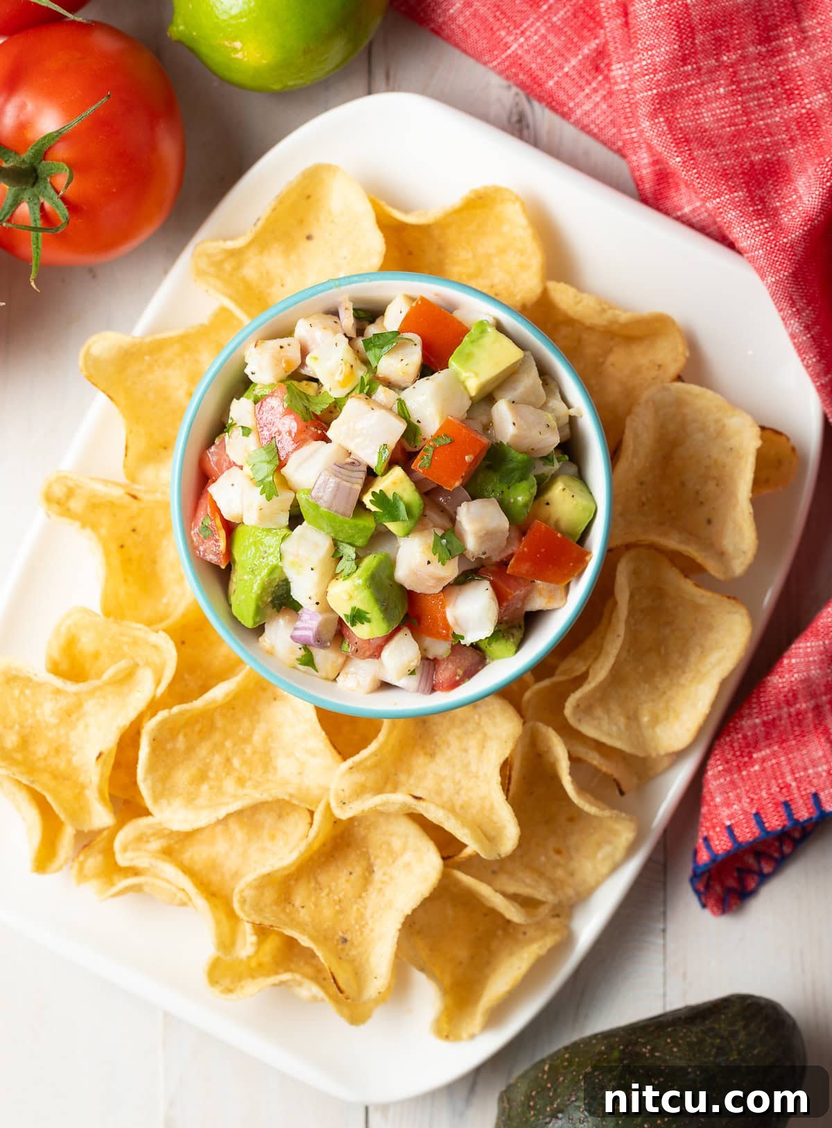 Ceviche de pescado overhead shot in small bowl on platter with tortilla chip scoops