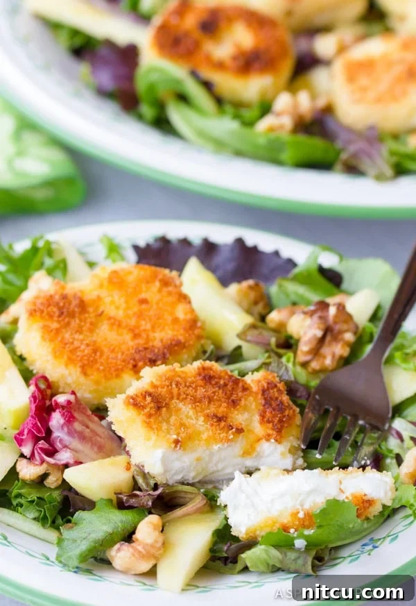 Warm Fried Goat Cheese Salad on a plate with a goat cheese round cut open to show its creamy interior.