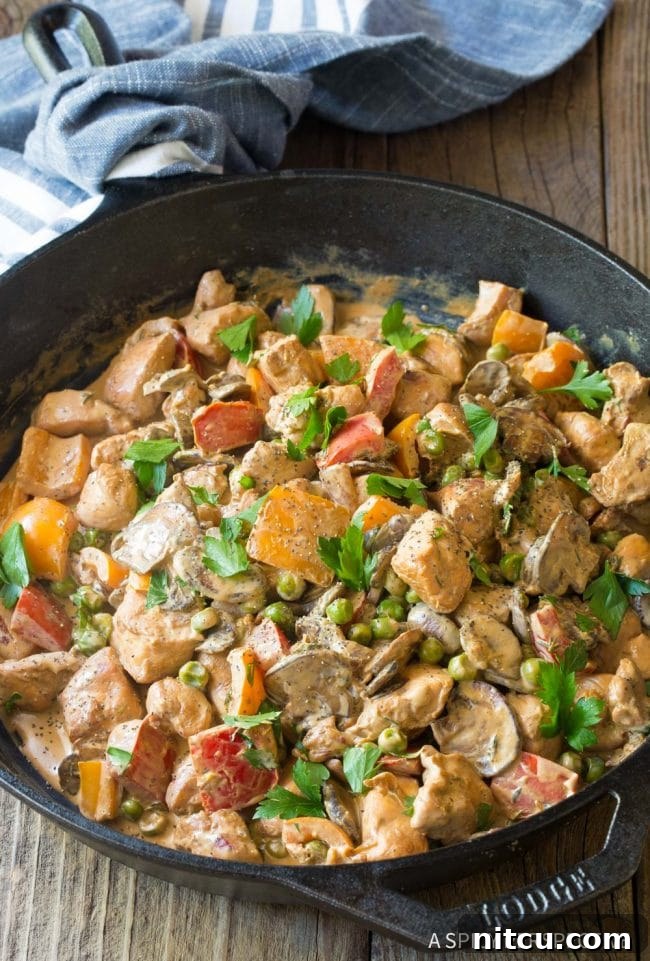 Creamy Healthy Chicken a la King in a cast iron skillet, garnished with fresh parsley.