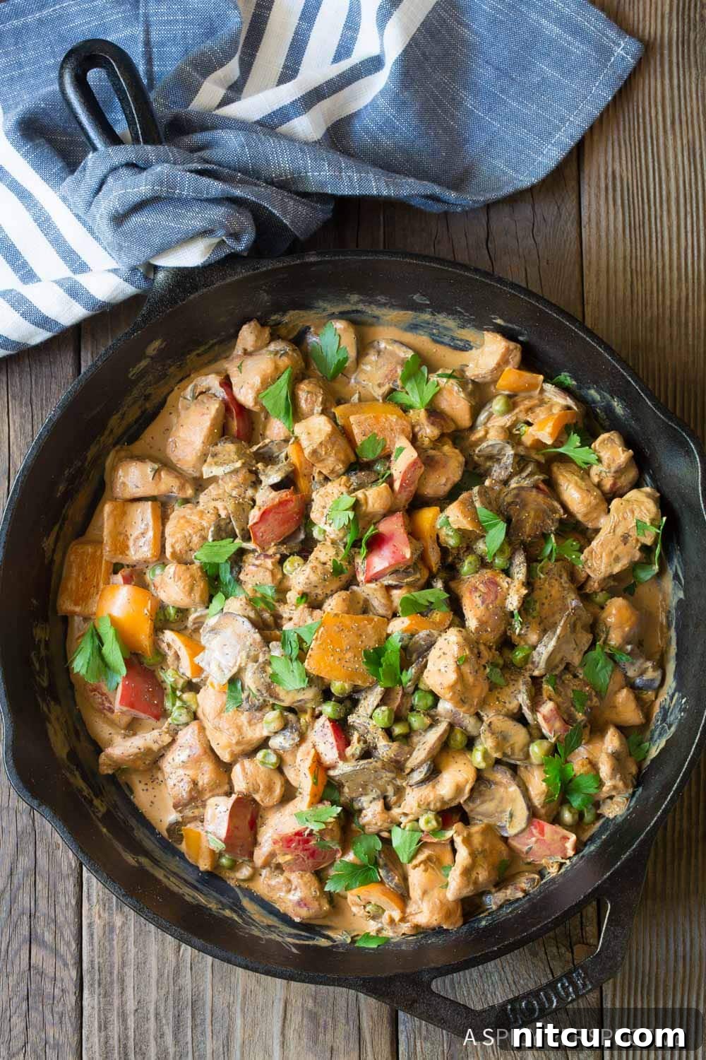 Healthy Chicken a la King in a cast iron skillet, garnished with fresh parsley.