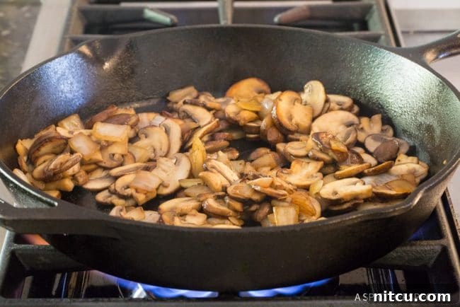 Mushrooms being sauteed until golden brown in a skillet.