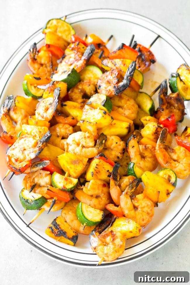 Top view of a platter full of these seafood skewers with vegetables. Grilled Teriyaki Shrimp Skewers are a perfect light and healthy summer dinner idea, packed with protein and fresh produce.
