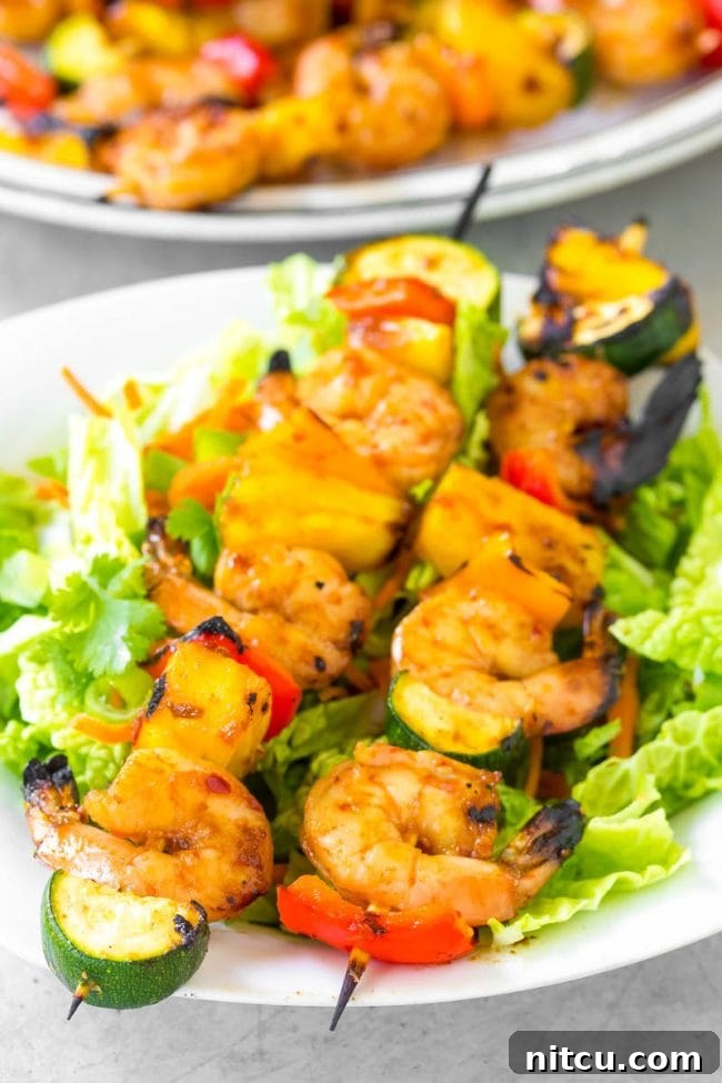 Closeup shot of perfectly cooked shrimp skewers on a white plate, showcasing their vibrant colors and juicy appearance.