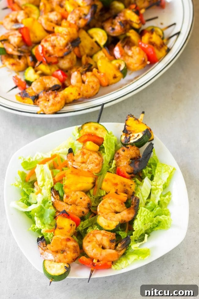 Top view of two perfectly grilled teriyaki shrimp skewers on a plate, showcasing their vibrant colors and juicy texture.