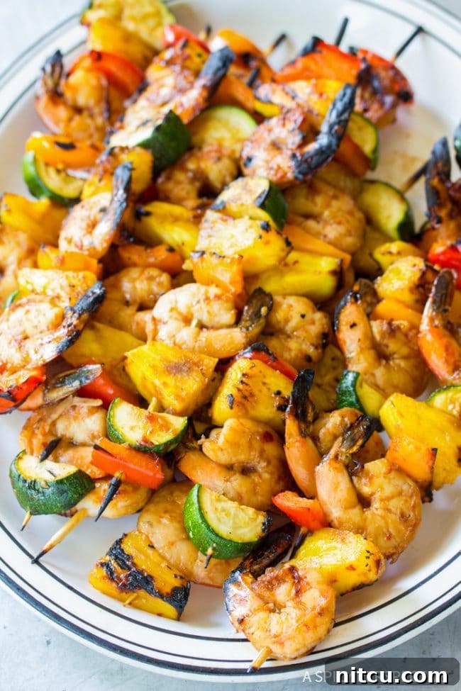 Closeup of perfectly cooked skewers of grilled teriyaki shrimp, with visible char marks and glistening sauce.