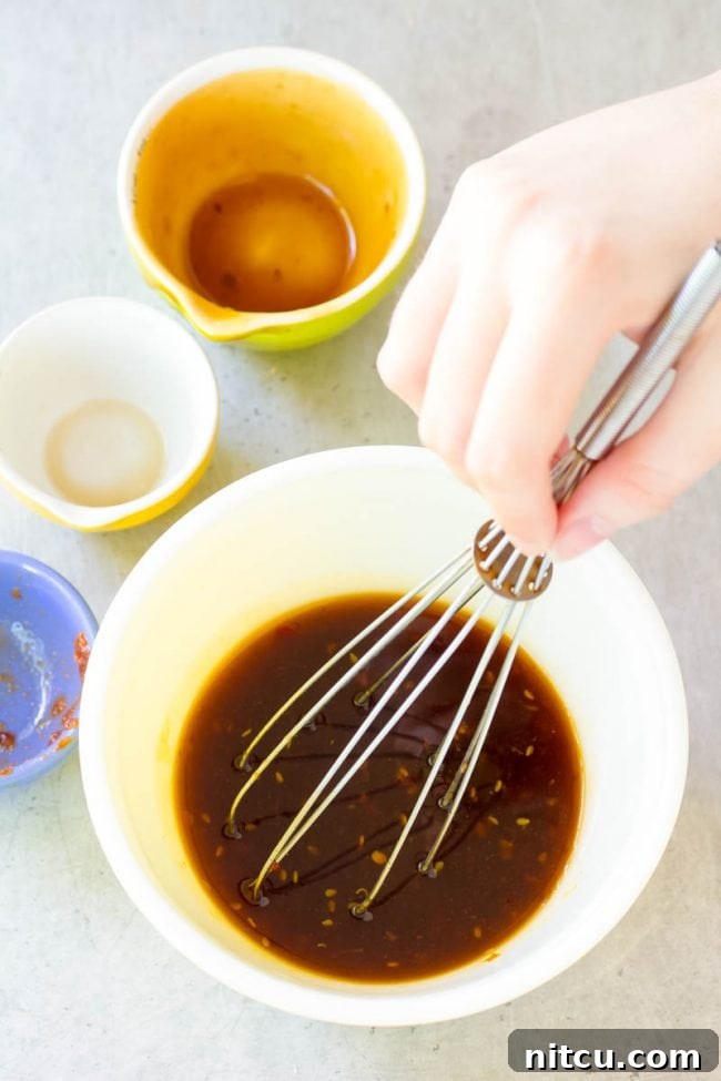 Overhead shot of a hand whisking ingredients for the teriyaki marinade in a bowl.