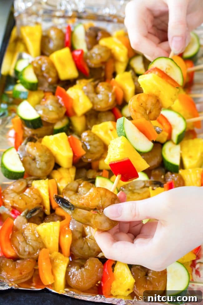 Closeup of a hand skillfully skewering shrimp and colorful vegetables onto wooden skewers.