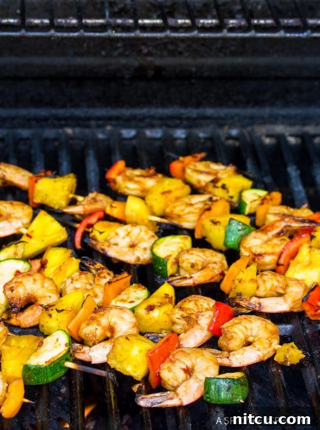Vibrant shrimp skewers grilling on an outdoor barbecue, with visible smoke and char.