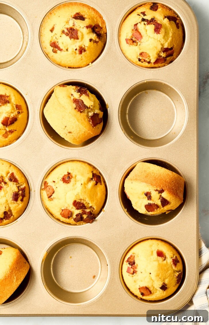Delicious warm cornbread muffins in a baking pan with bacon and maple syrup