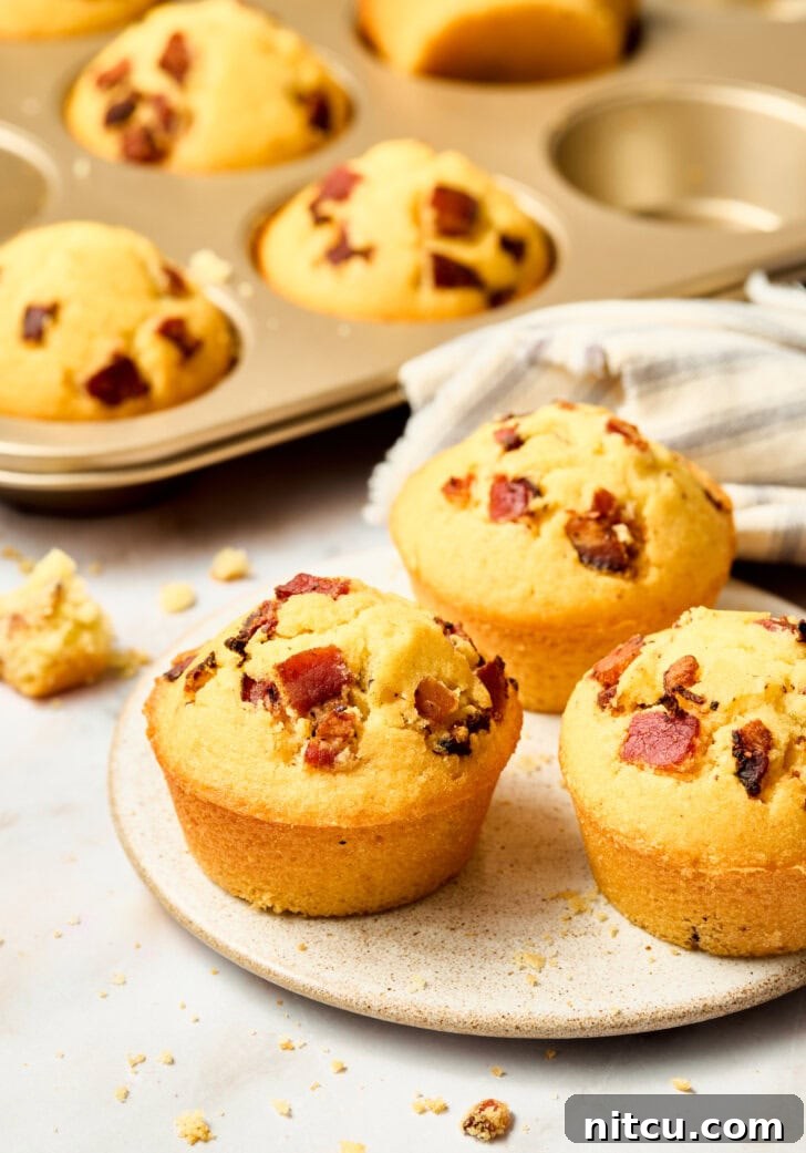 Easy cornbread muffins in a pan, topped with bacon and maple syrup