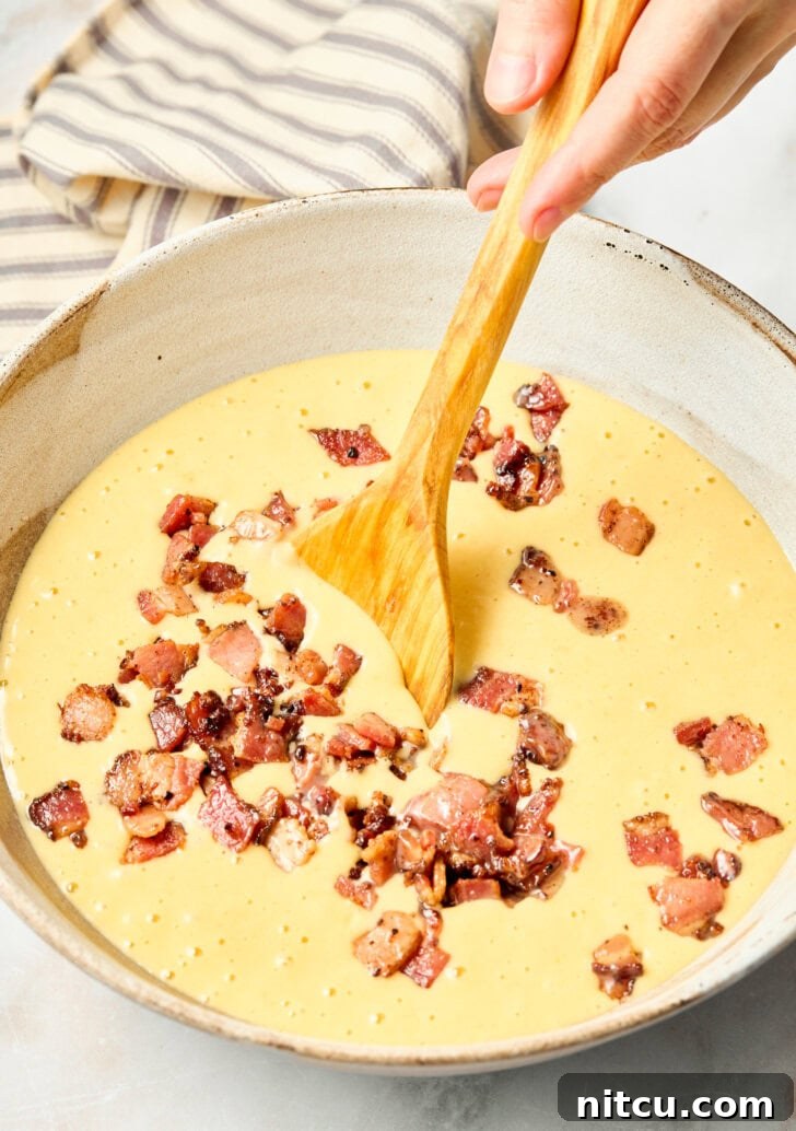 Chopped bacon mixed into cornbread muffin batter in a bowl