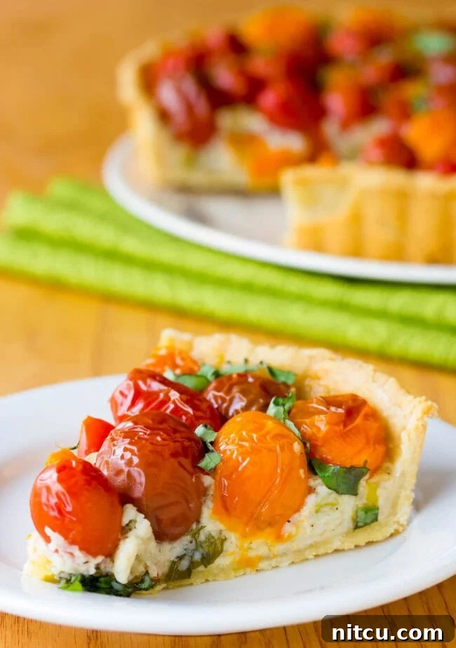A cross-section of the tomato tart, revealing all the beautiful layers of crust, creamy cheese filling, and fresh tomatoes.