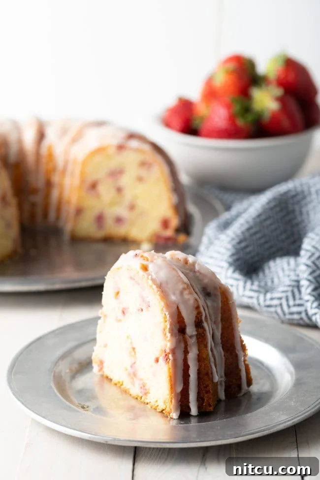A delectable slice of strawberry lemon bundt cake on a silver plate, showing off its tender crumb and rich strawberry distribution.