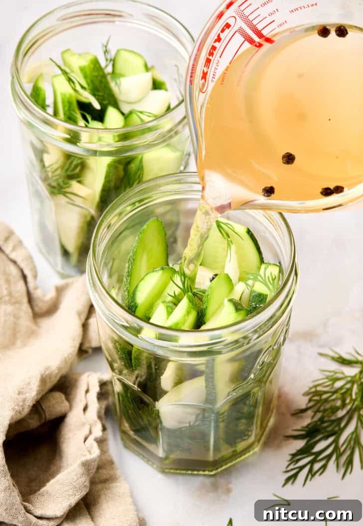 Refrigerator Pickles in jar up close - warm brine being poured into jars over packed cucumbers and spices
